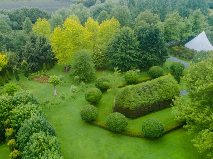 Aerial view of garden with living structure and tent visible among trees