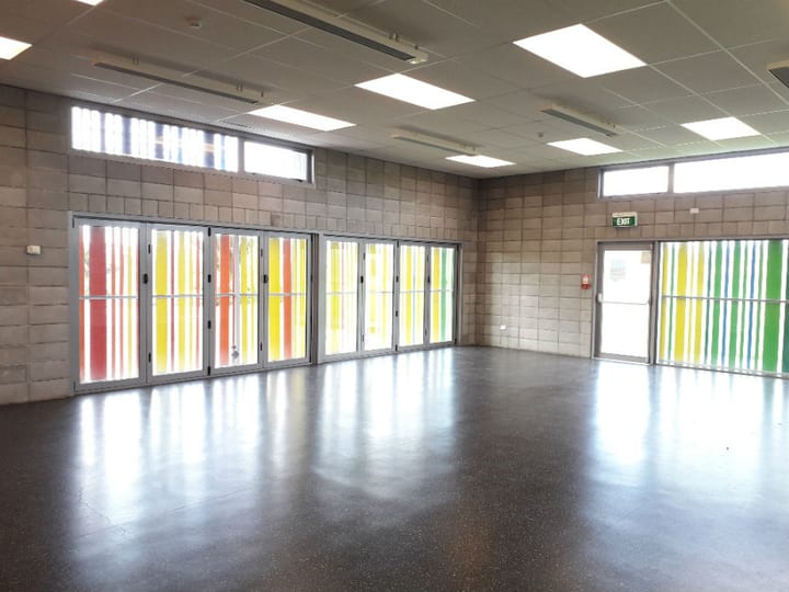 Open hall with concrete block walls, coloured glazed folding doors, and polished concrete floor