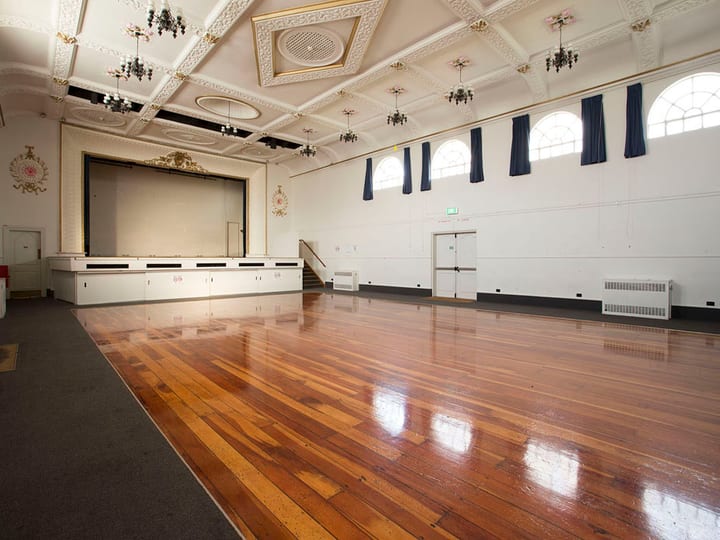 Grand hall with polished floor, ornate plasterwork ceiling and raised platform
