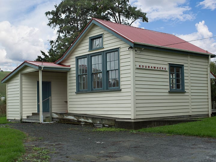 Small weatherboard hall with red roof and covered entry porch