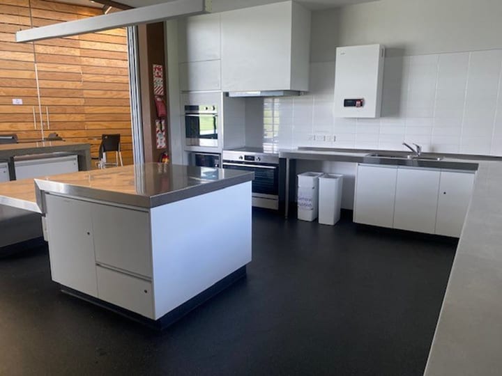 Community kitchen with white cabinetry, stainless island, and large fridge
