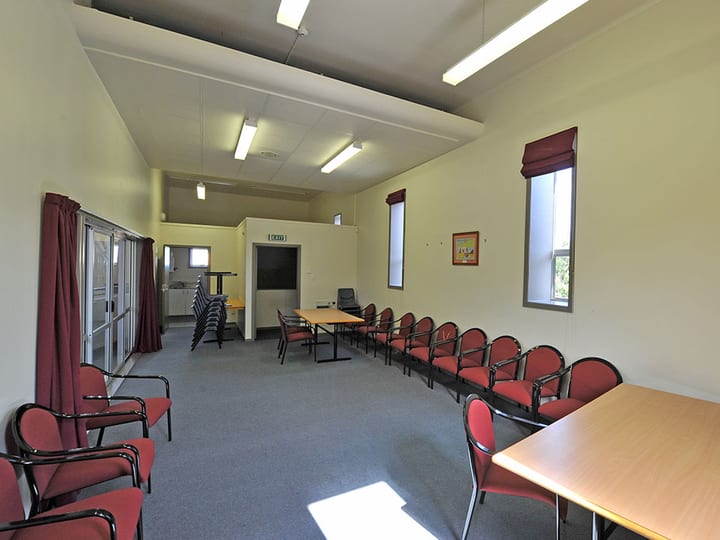 Meeting room with tables arranged in rows, carpet and multiple windows