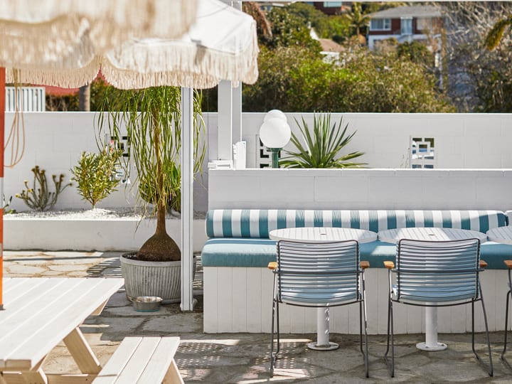 Outdoor courtyard with umbrella, bench seating and decorative neon sign on pink wall