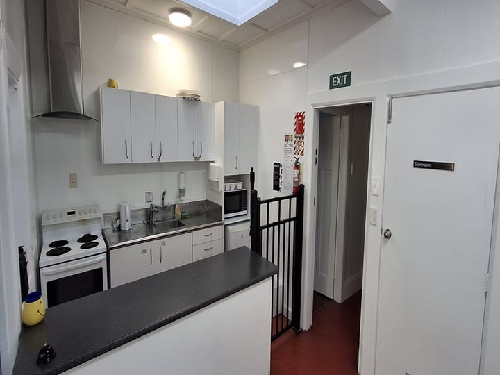 Kitchen with white cabinets, stove, refrigerator and dark bench tops