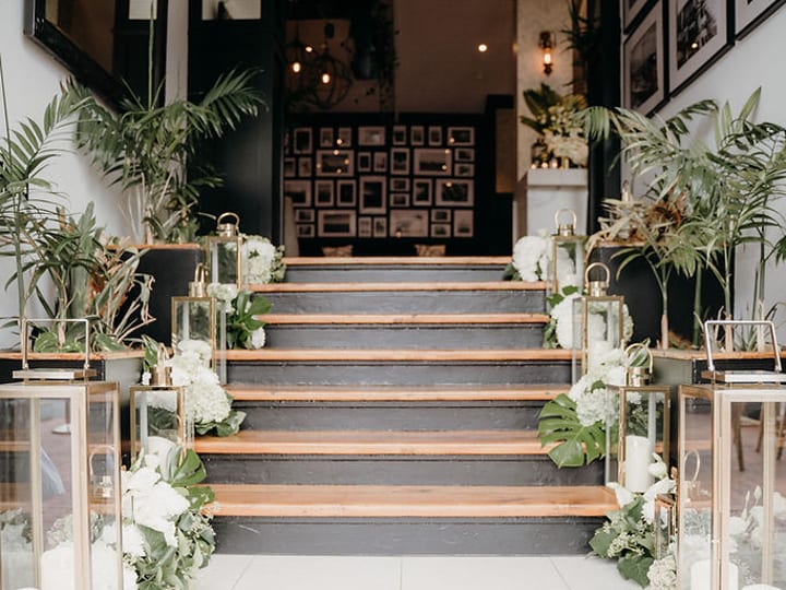 Staircase decorated with lanterns, white flowers and trailing greenery in a venue entrance
