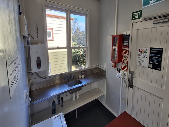 Small utility room with stainless sink, fire action panel and exit door