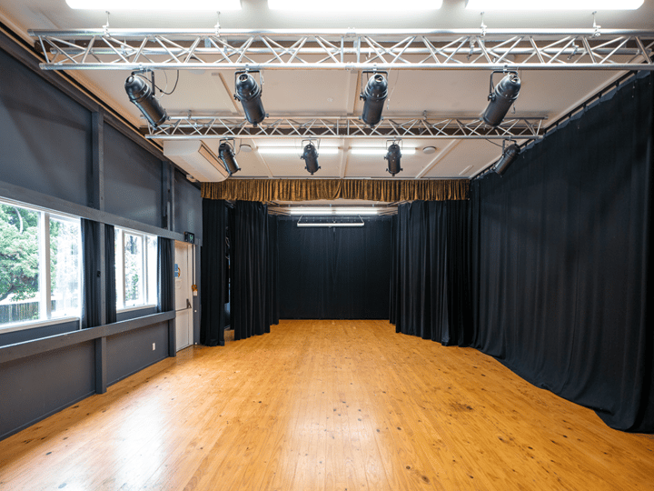 Black-curtained studio space with timber floor, overhead lighting rigs, and track spotlights
