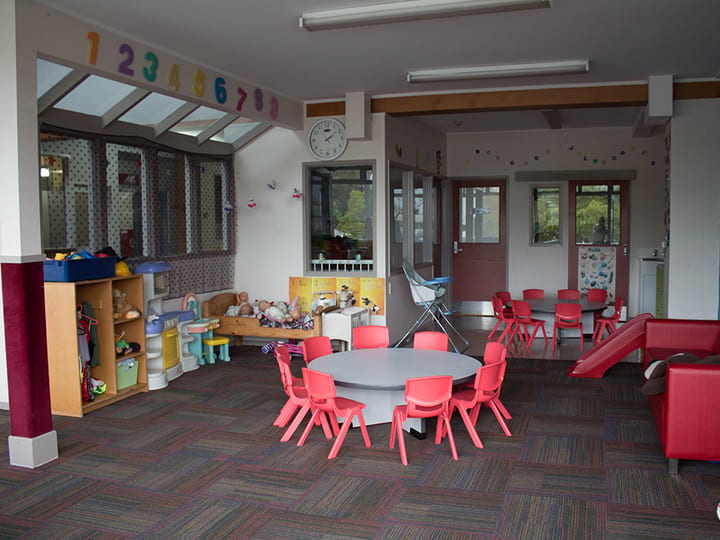 Children's playroom with small tables, colourful chairs and toy shelves