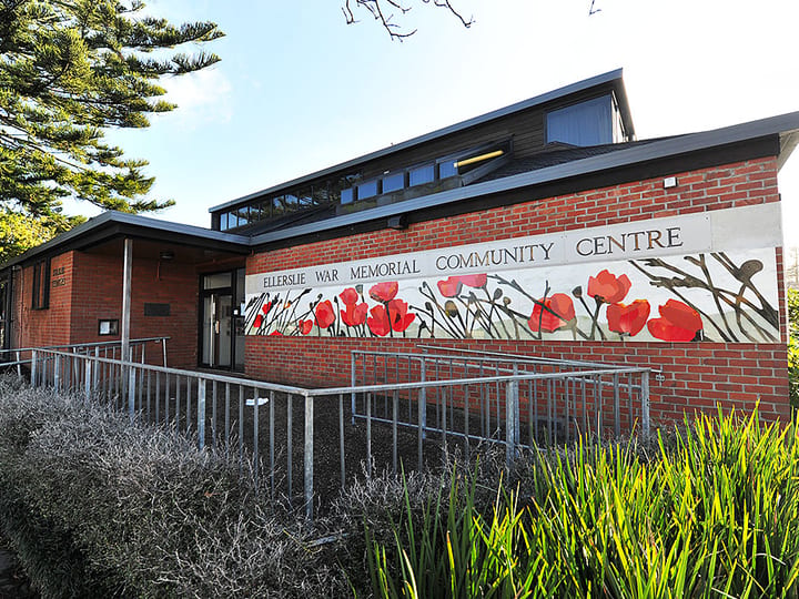 Brick community centre building with painted poppy mural across the facade