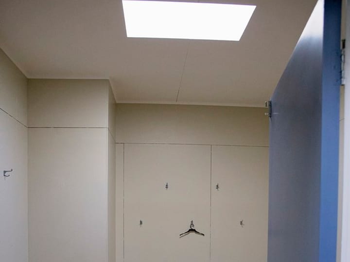 Plain changing room with built-in lockers, bench and skylight