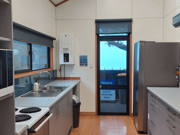 Kitchen with white cabinetry, stainless bench, microwave and door to exterior