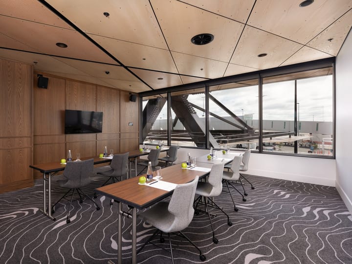Modern meeting room with timber wall panels, screen, and views of an airport tarmac