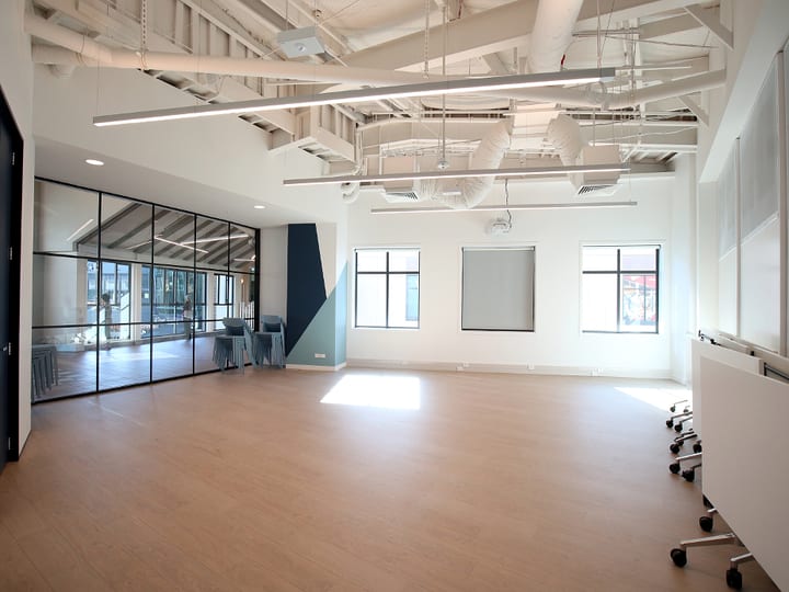 Open activity room with timber floor, whiteboards on wheels, and glass wall