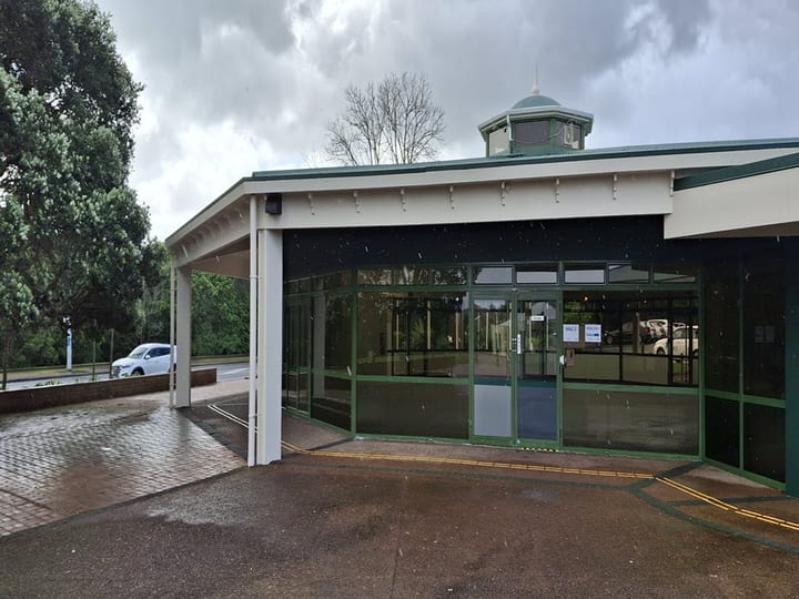 Hall entrance with glazed facade, overhanging canopy, and octagonal tower detail