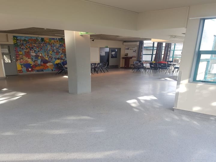 Open hall interior with concrete floor, table and chairs, large mural on side wall