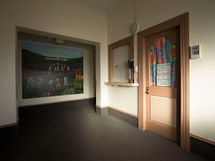 Narrow corridor with grey carpet, a large wall painting, and a timber-framed doorway