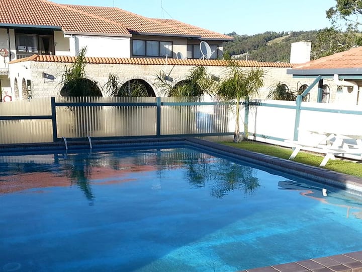 Outdoor swimming pool with motel building and hills in the background