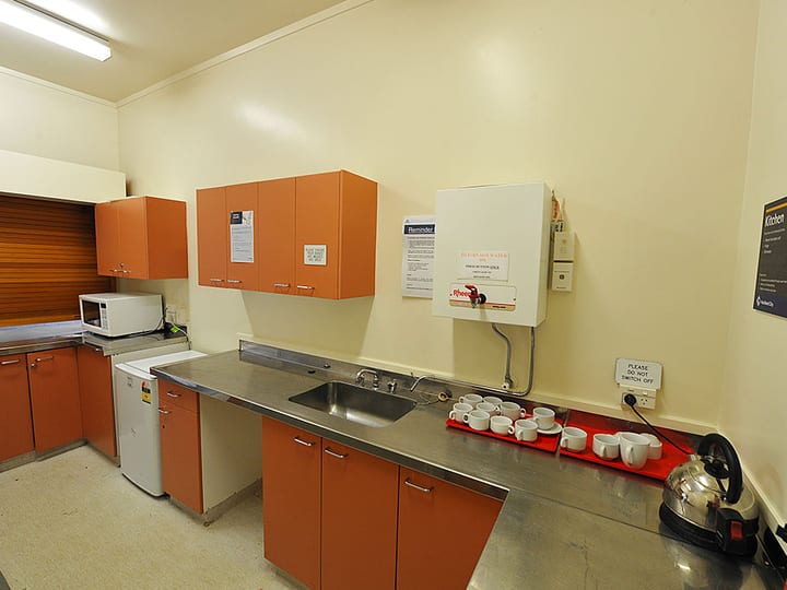 Small hall kitchen with orange cabinetry, microwave and benchtop
