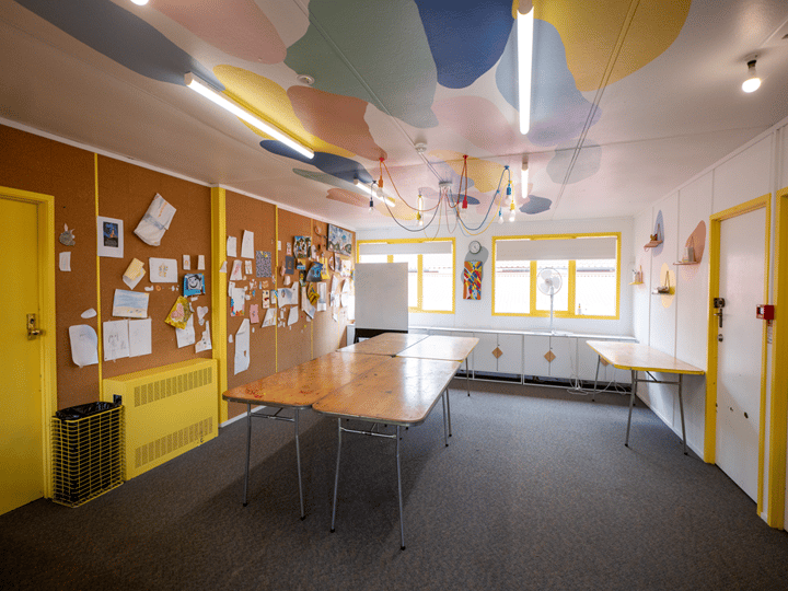 Colourful activity room with cork boards, pastel ceiling and trestle tables