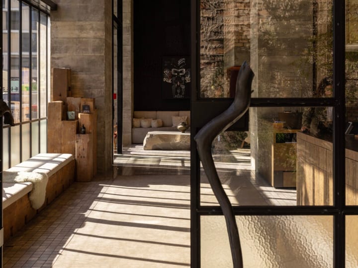 Hotel interior with raw concrete, exposed brick and timber through glass partitions