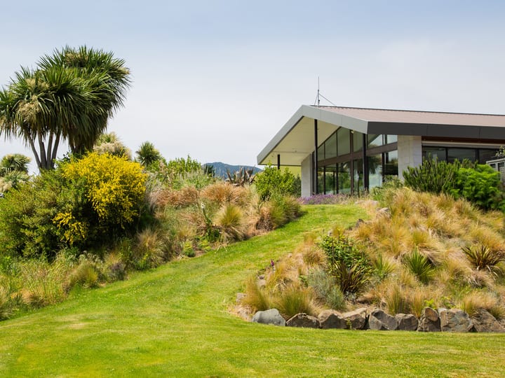 Landscaped garden with native plantings and lodge building with large windows