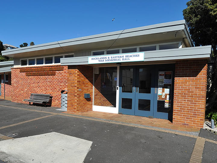 Single-storey brick hall with blue entrance doors and signage above