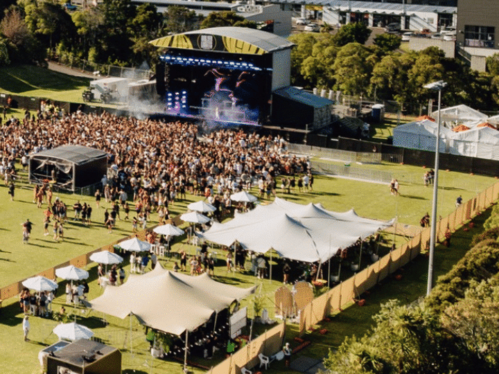 Aerial view of outdoor concert event on lawn beside arena building