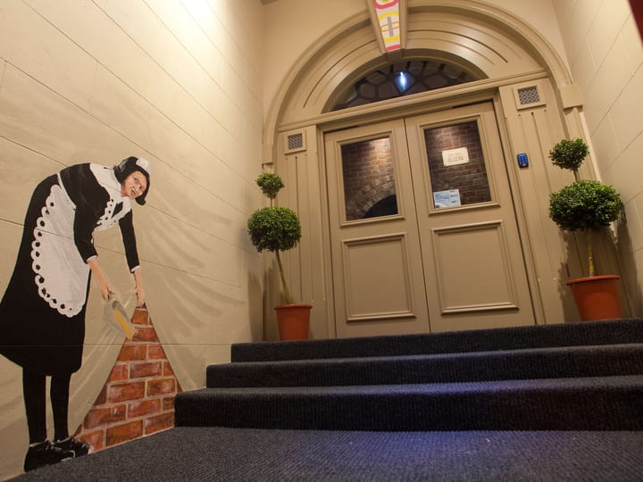 Arched entry corridor with carpet stairs, potted topiaries and painted mural artwork