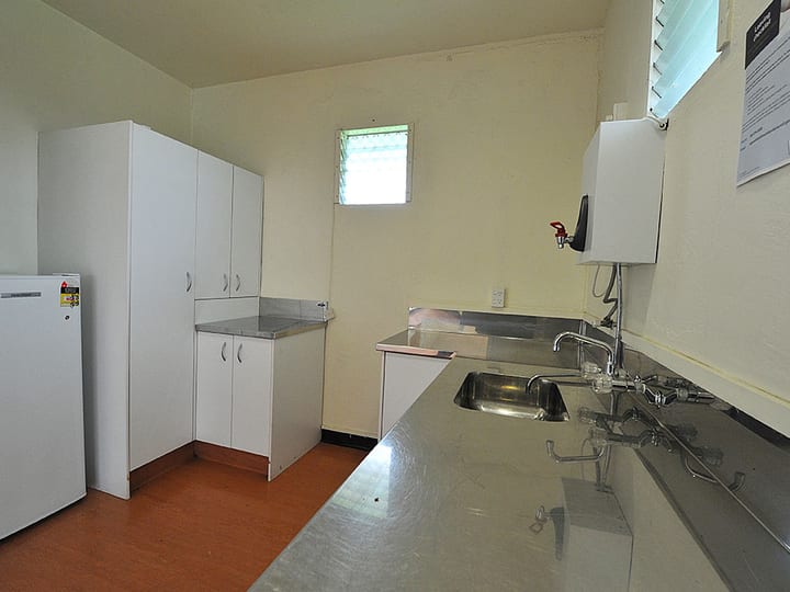 Narrow kitchen with stainless benchtops, fridge and single window