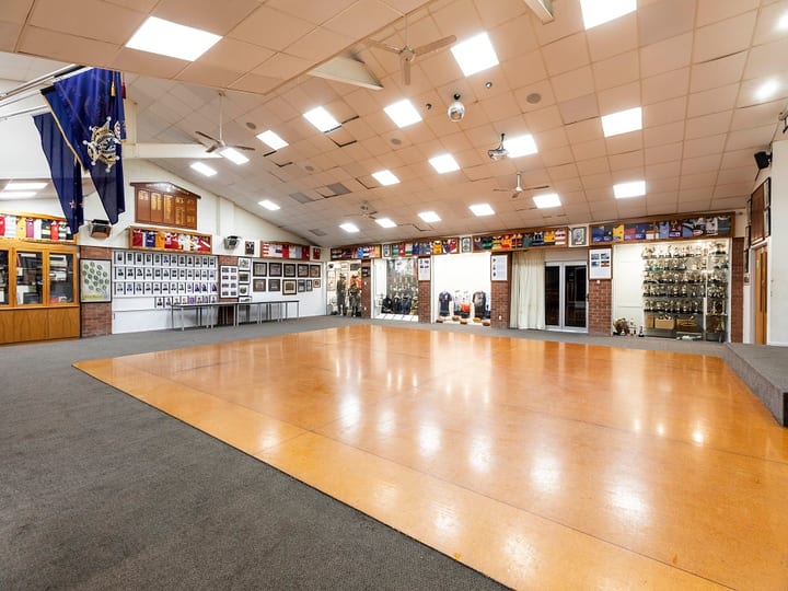 Large function room with dance floor, trophies on display, and club memorabilia on walls