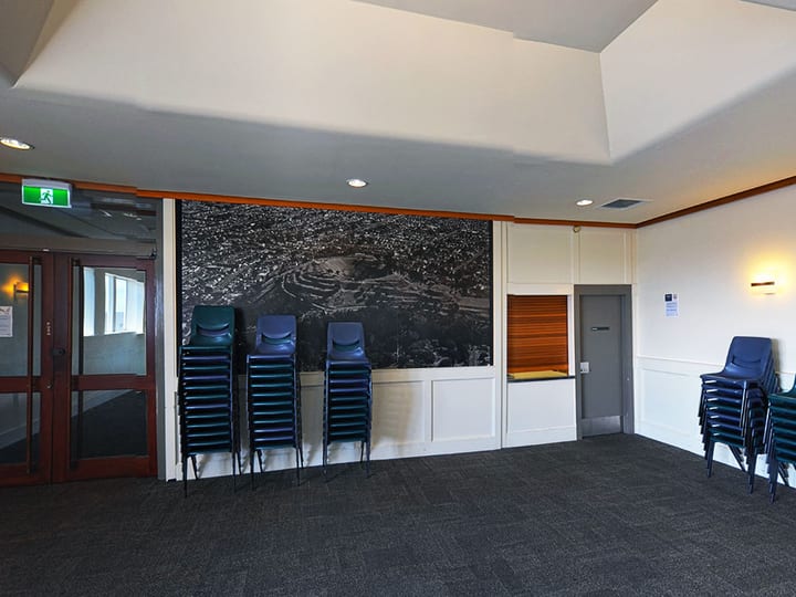 Hall foyer with stacked chairs and large aerial photograph on wall