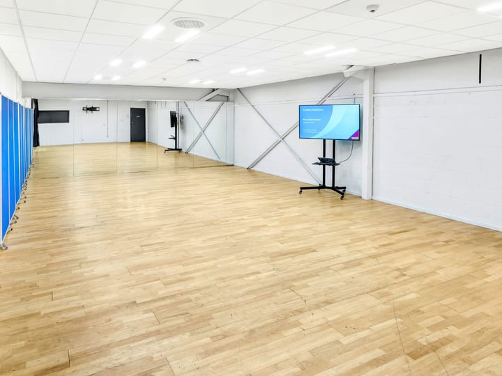 Plain rectangular hall with timber floor, wall mirrors, and a freestanding screen