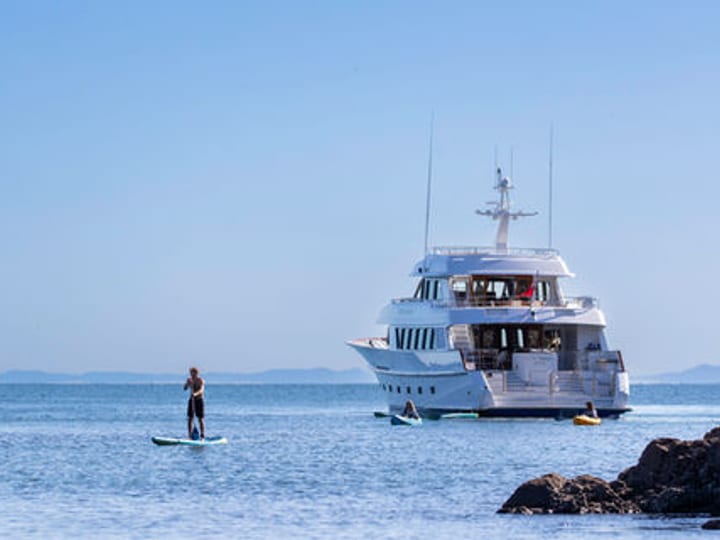Yacht saloon with sofas, armchairs and open deck dining beyond