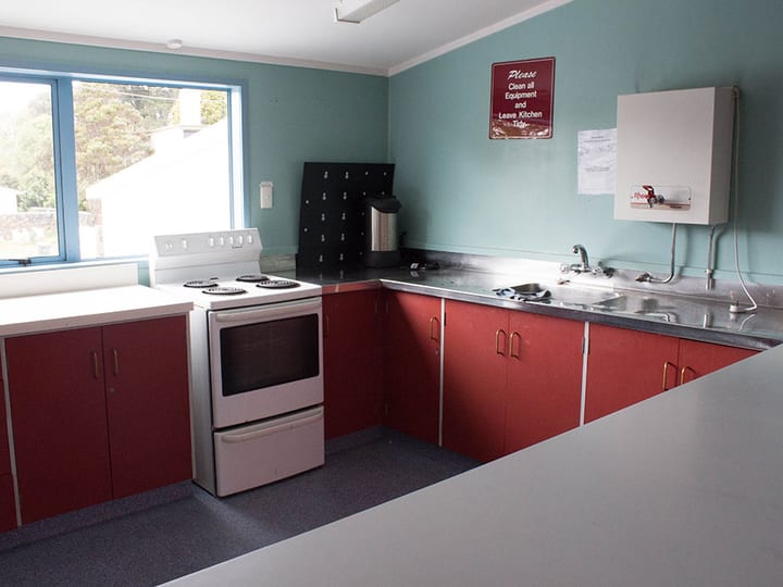 Bright kitchen with red cabinetry, stove and benchtop