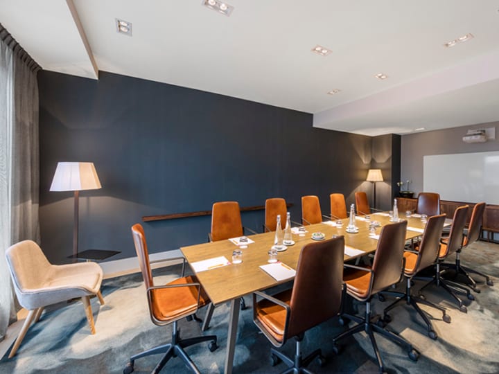 Hotel meeting room with long table, leather chairs, and dark feature wall