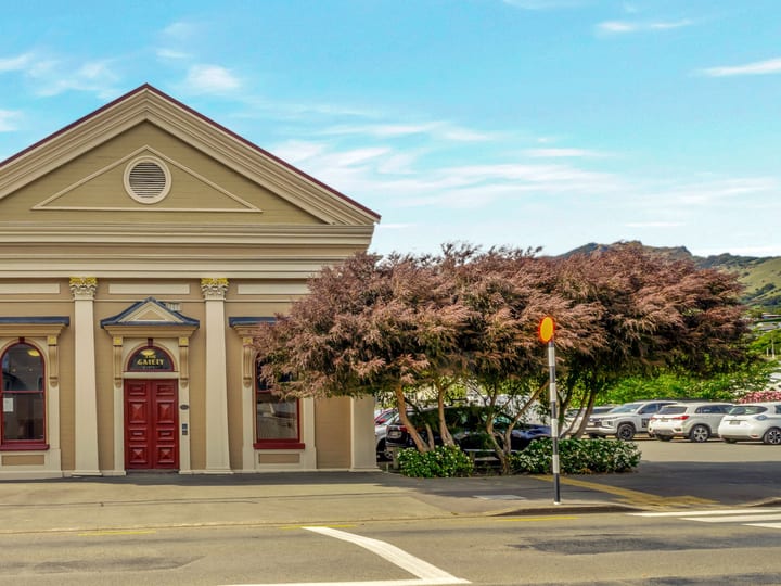 Cream rendered heritage building with classical columns, triangular pediment, red double doors