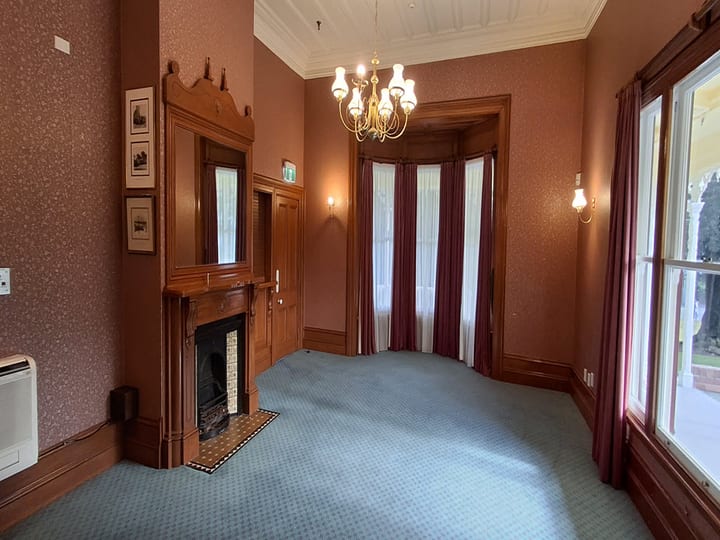 Victorian room with fireplace, bay window, chandelier and red drapes