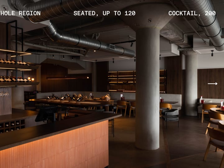 Industrial-style dining room with concrete columns, backlit wine racks, and timber banquettes