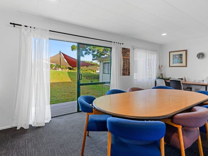 Meeting room with oval table, blue and purple chairs, and sliding door to grass lawn
