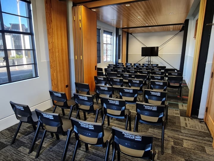 Meeting room with chairs in rows facing a screen and timber slat feature wall
