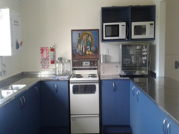 Basic kitchen with blue cabinets, stove, and microwave