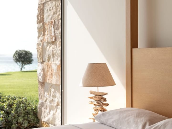 Bedroom with stone wall, timber ceiling and sea view