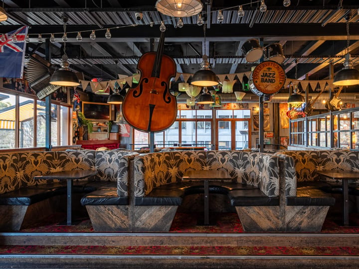 Interior bar seating with large cello hanging overhead and patterned upholstered booths