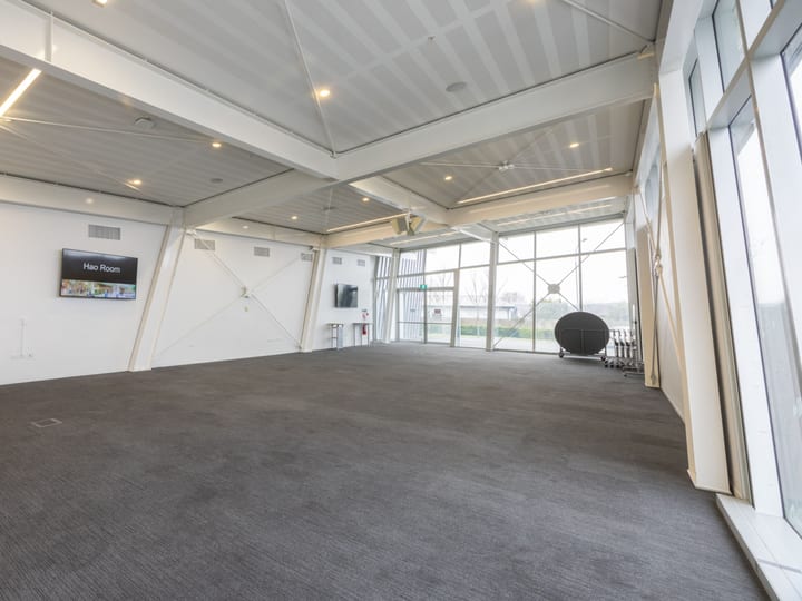Large open hall with carpeted floor, angled ceiling and glazed wall