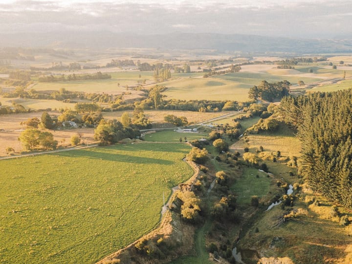 Wide aerial view of rolling farmland with hills and river valley at golden hour