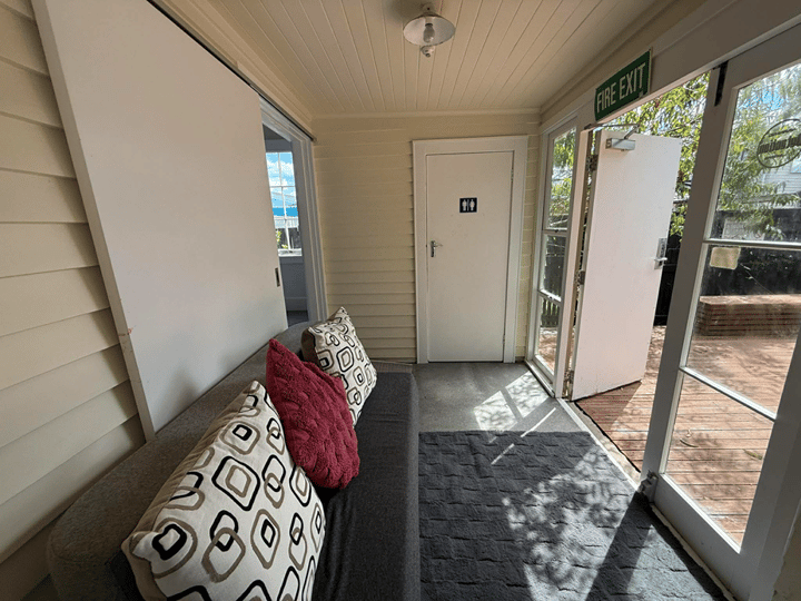 Entry verandah of timber community house with French doors open