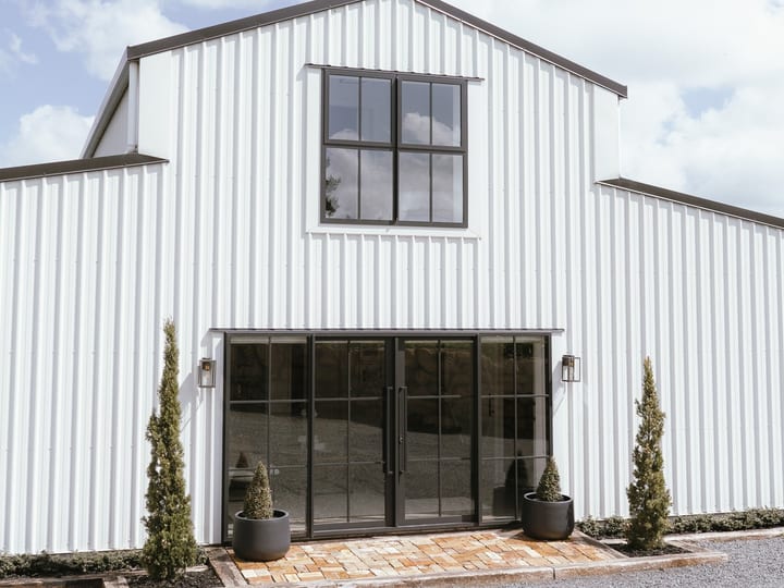 White steel barn building with black-framed glazed entry doors