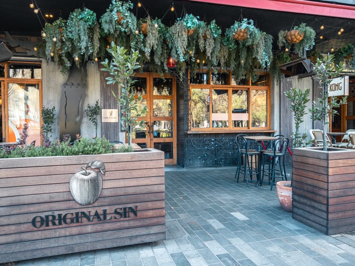 Restaurant exterior with hanging greenery, timber planter box with branding, and outdoor seating