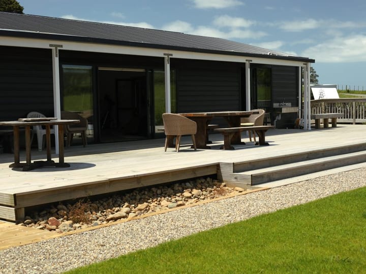 Dark-clad building with timber deck, outdoor furniture and lawn