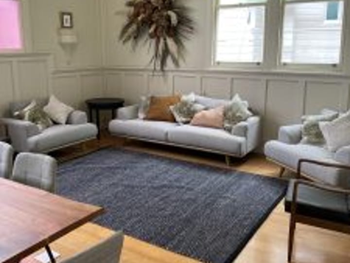 Bright room with arched windows, sofa seating, timber floor, and dining table
